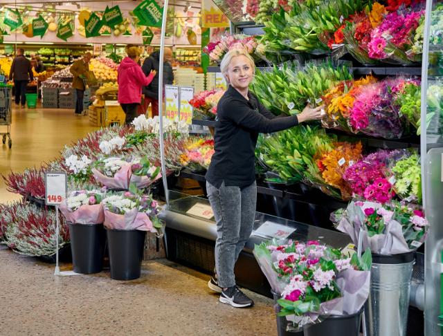 Kvinna placerar ut färgglada buketter i en butik